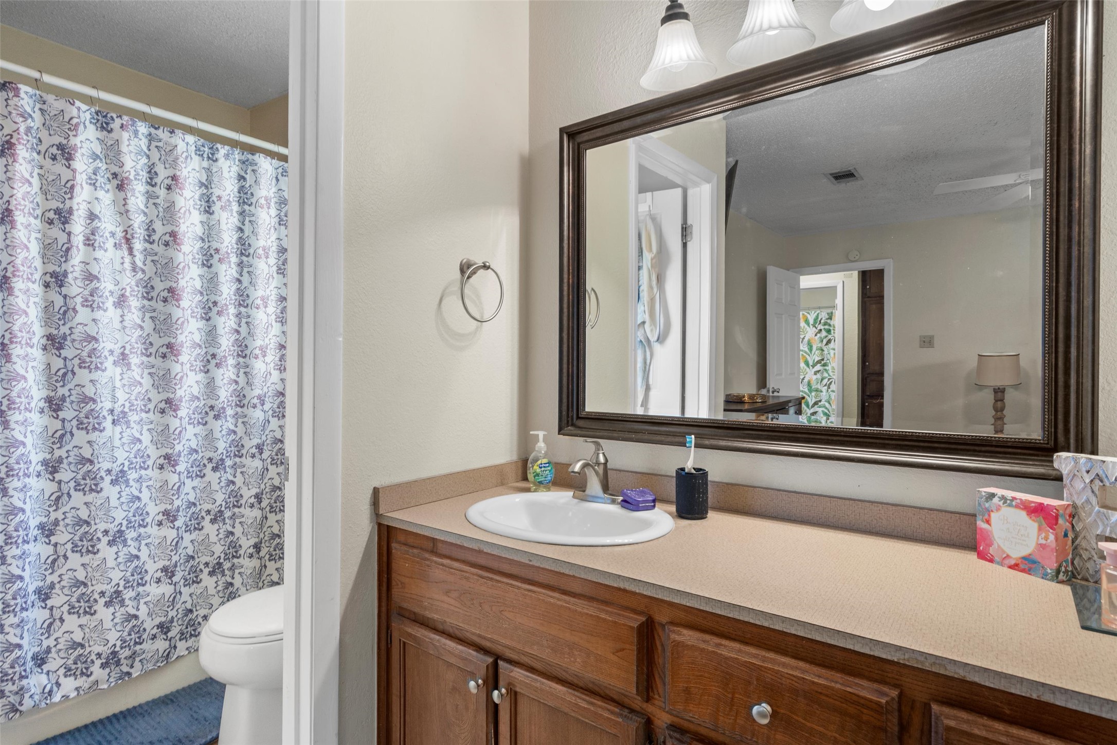6492 Hart Lane Austin, TX 78731 - Photo 14 of 22 Bathroom with vanity, a shower with curtain, and a textured ceiling