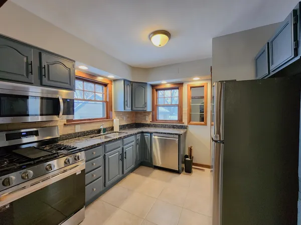 a kitchen with stainless steel appliances granite countertop a refrigerator and a stove top oven