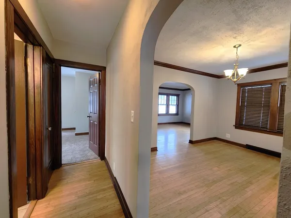 a view of a hallway with wooden floor and a kitchen