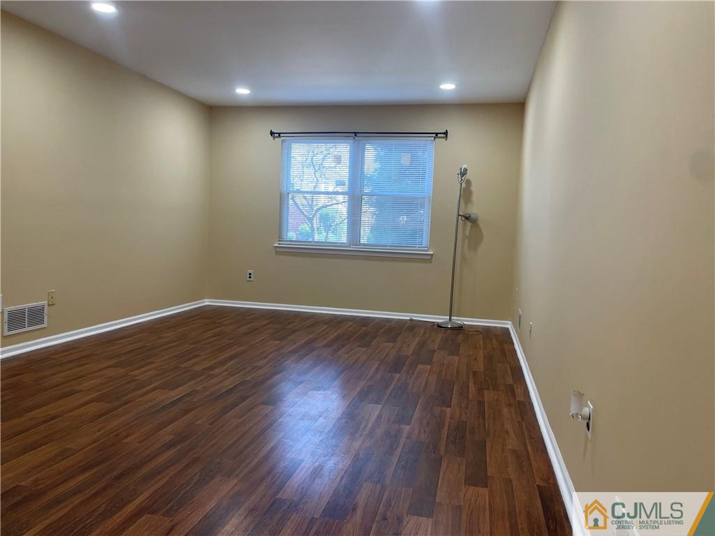 93 C Woodbridge Terrace, Unit 9303 Woodbridge, NJ 07095 - Photo 8 of 14 an empty room with wooden floor and windows