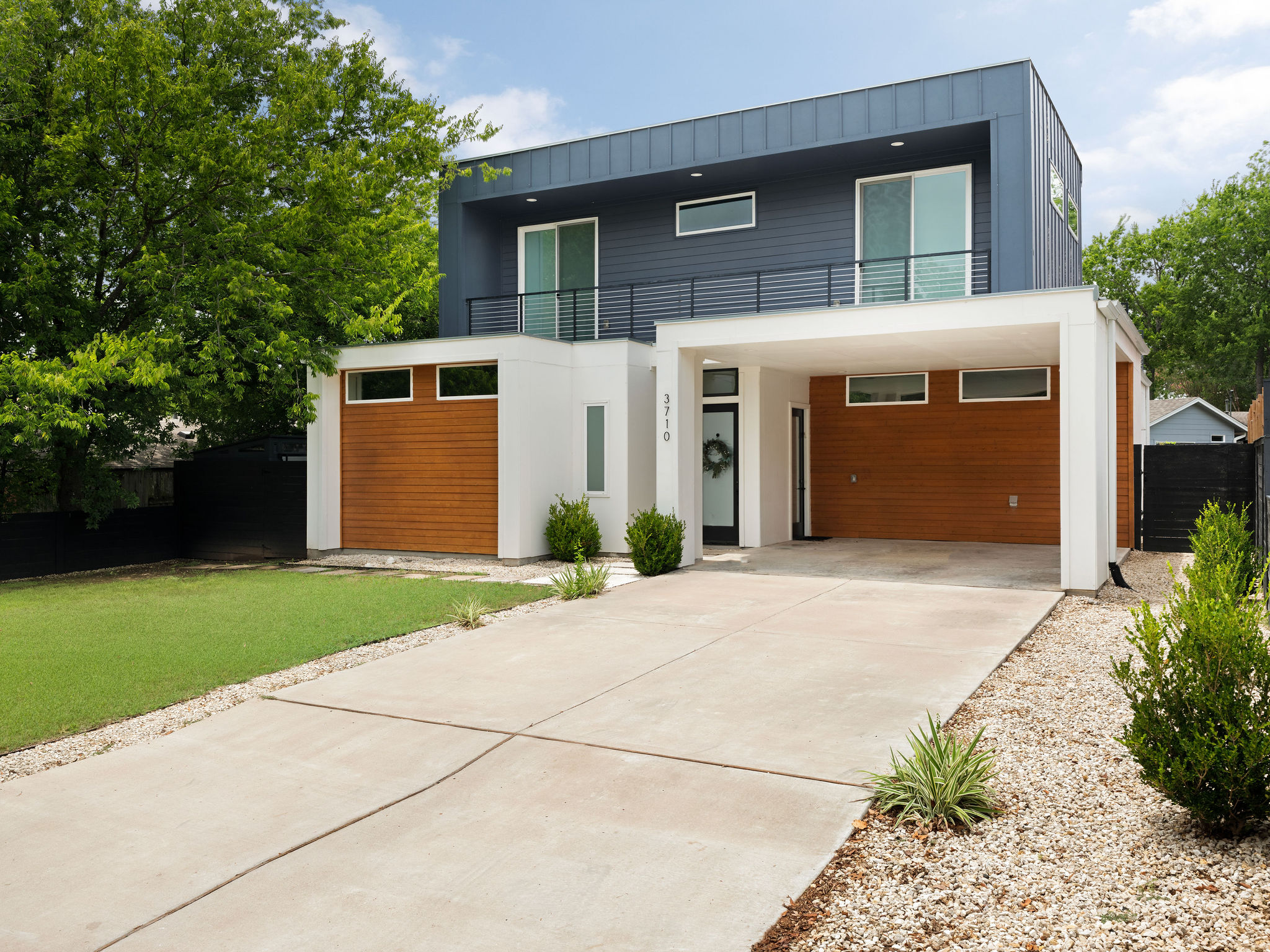 A modern facade with a striking blue upper level and warm wood accents create compelling curb appeal.