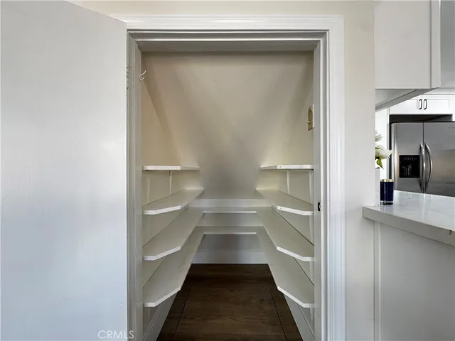 a view of a hallway with wooden floor and cabinets