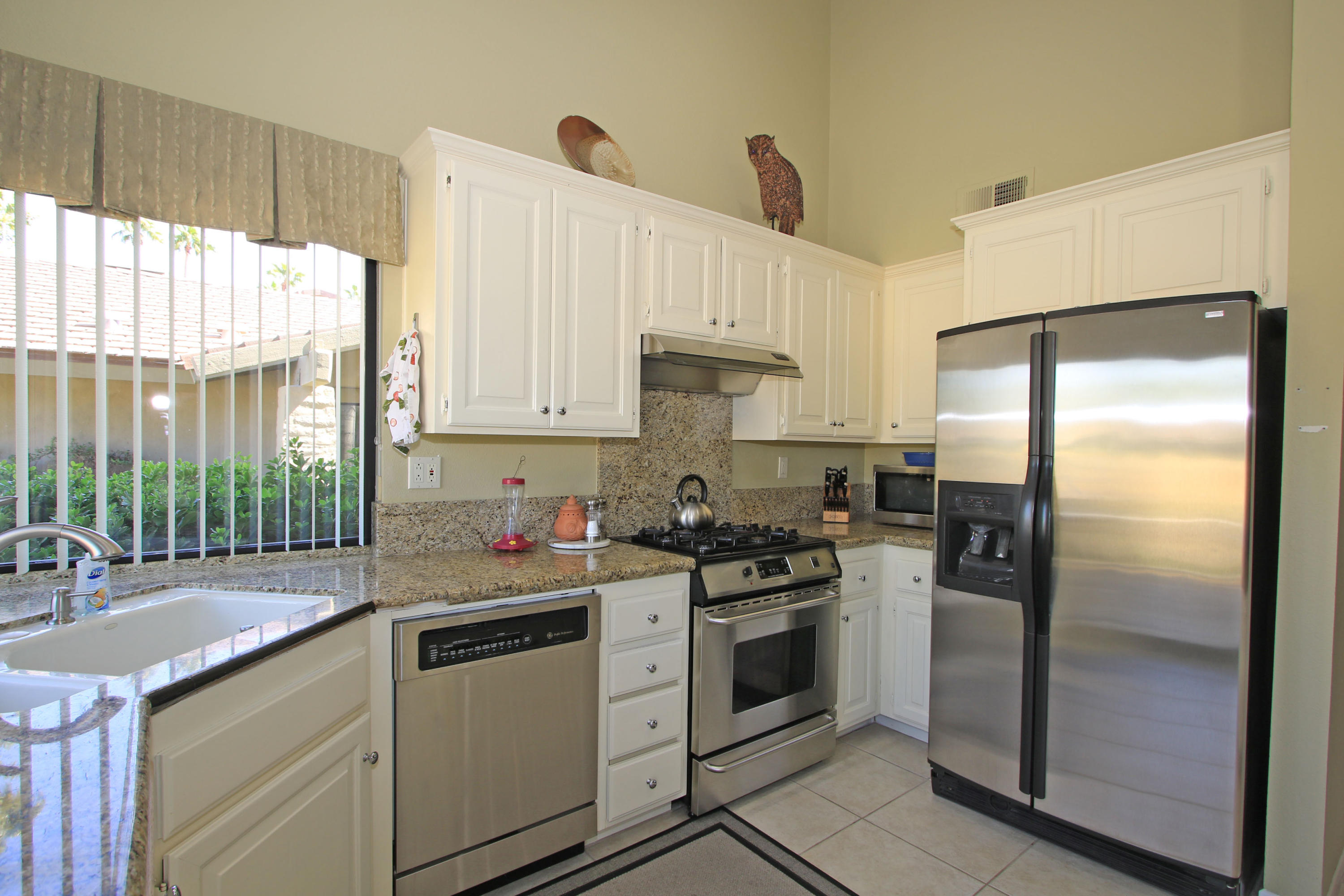 368 Red River Road Palm Desert, CA 92211 - Photo 14 of 36 a kitchen with white cabinets and stainless steel appliances