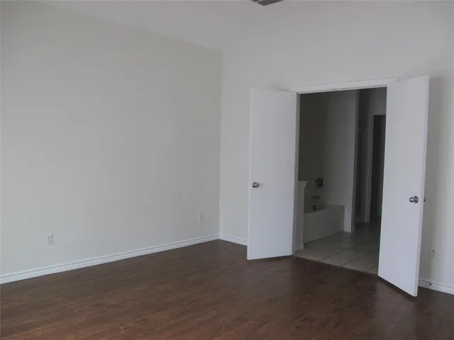a view of an empty room with wooden floor and closet