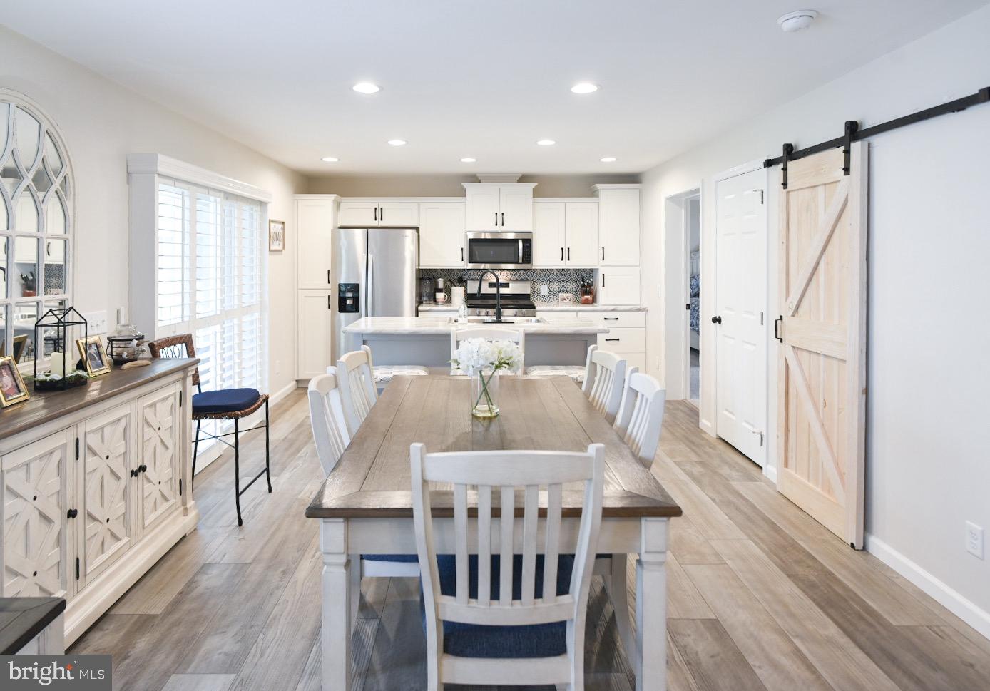 33510 Deer Run Road Frankford, DE 19945 - Photo 6 of 53 a kitchen with stainless steel appliances kitchen island granite countertop a refrigerator a stove a microwave oven a dining table and chairs with wooden floor