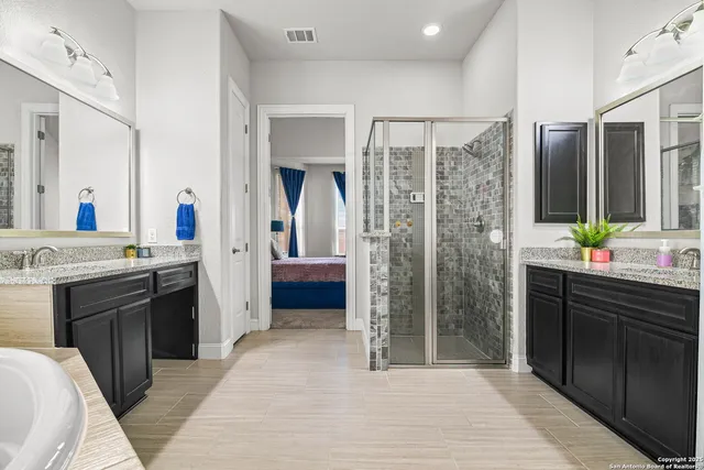 a large bathroom with a double vanity sink a large mirror and a shower