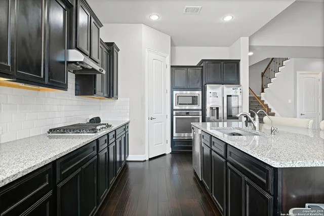 a kitchen with stainless steel appliances granite countertop a sink stove and refrigerator