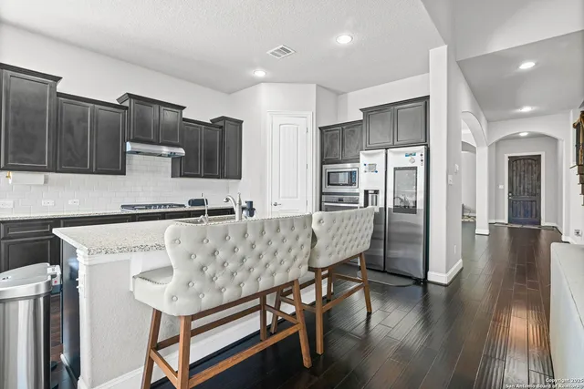 a kitchen with stainless steel appliances granite countertop a refrigerator and a stove top oven