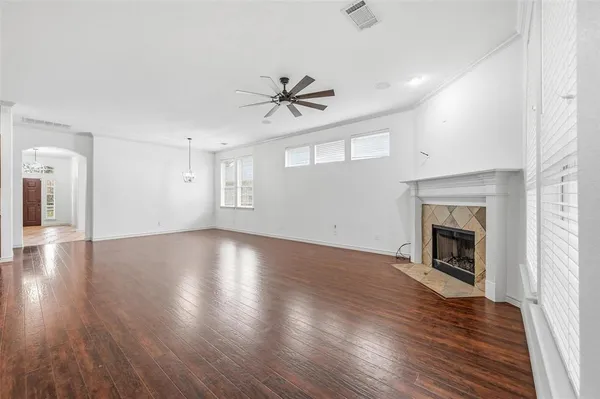 an empty room with wooden floor fireplace and windows
