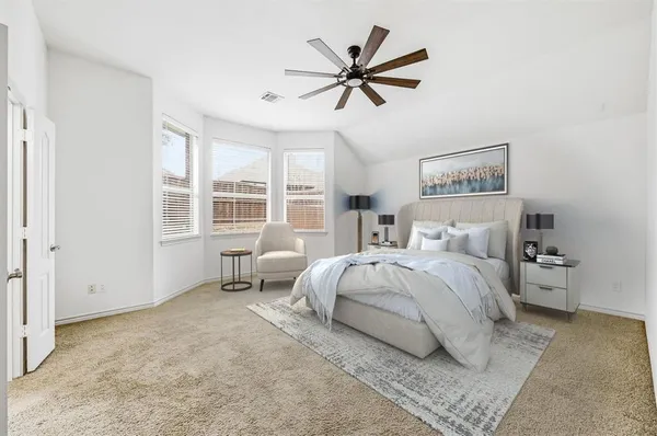 a bedroom with a large bed and a chandelier fan