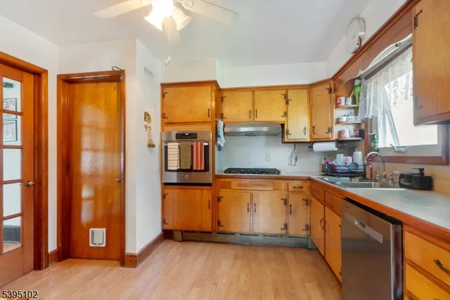 a kitchen with stainless steel appliances granite countertop a refrigerator a sink a stove and white cabinets with wooden floor