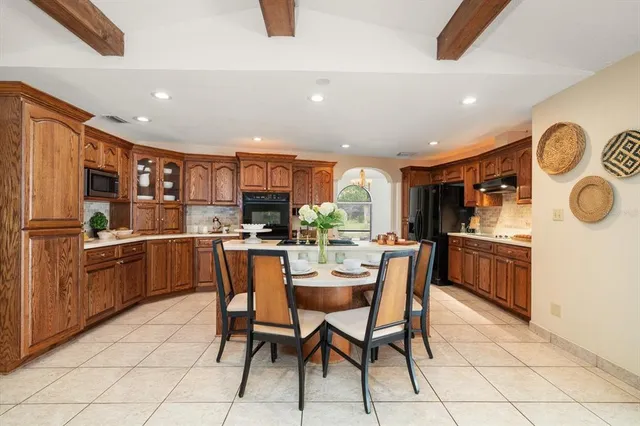 a kitchen with stainless steel appliances granite countertop a stove a sink a refrigerator and chairs