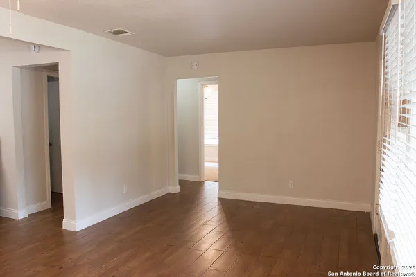an empty room with wooden floor and windows