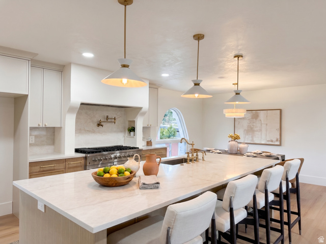 1860 Spring Lane Holladay, UT 84117 - Photo 4 of 32 Kitchen featuring a large central island with seating, a built-in range, a pot filler, pendant lighting, and an arched window