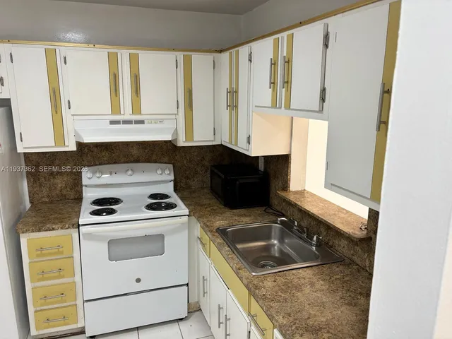 a kitchen with a stove sink and cabinets