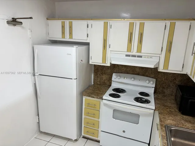 a kitchen with a refrigerator stove and white cabinets