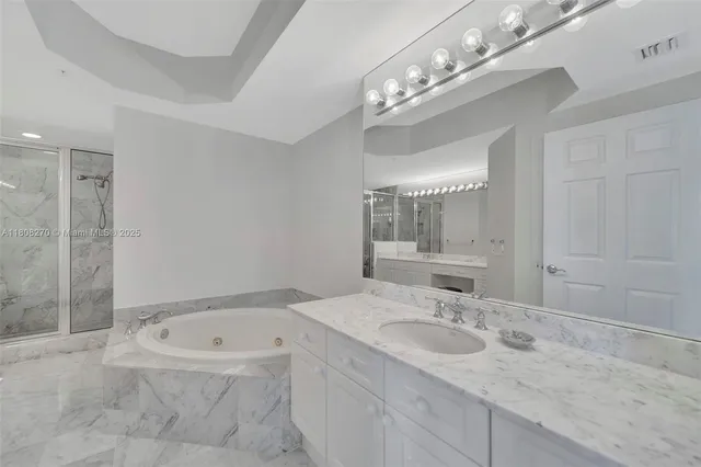 a bathroom with a granite countertop sink a large mirror and a bathtub