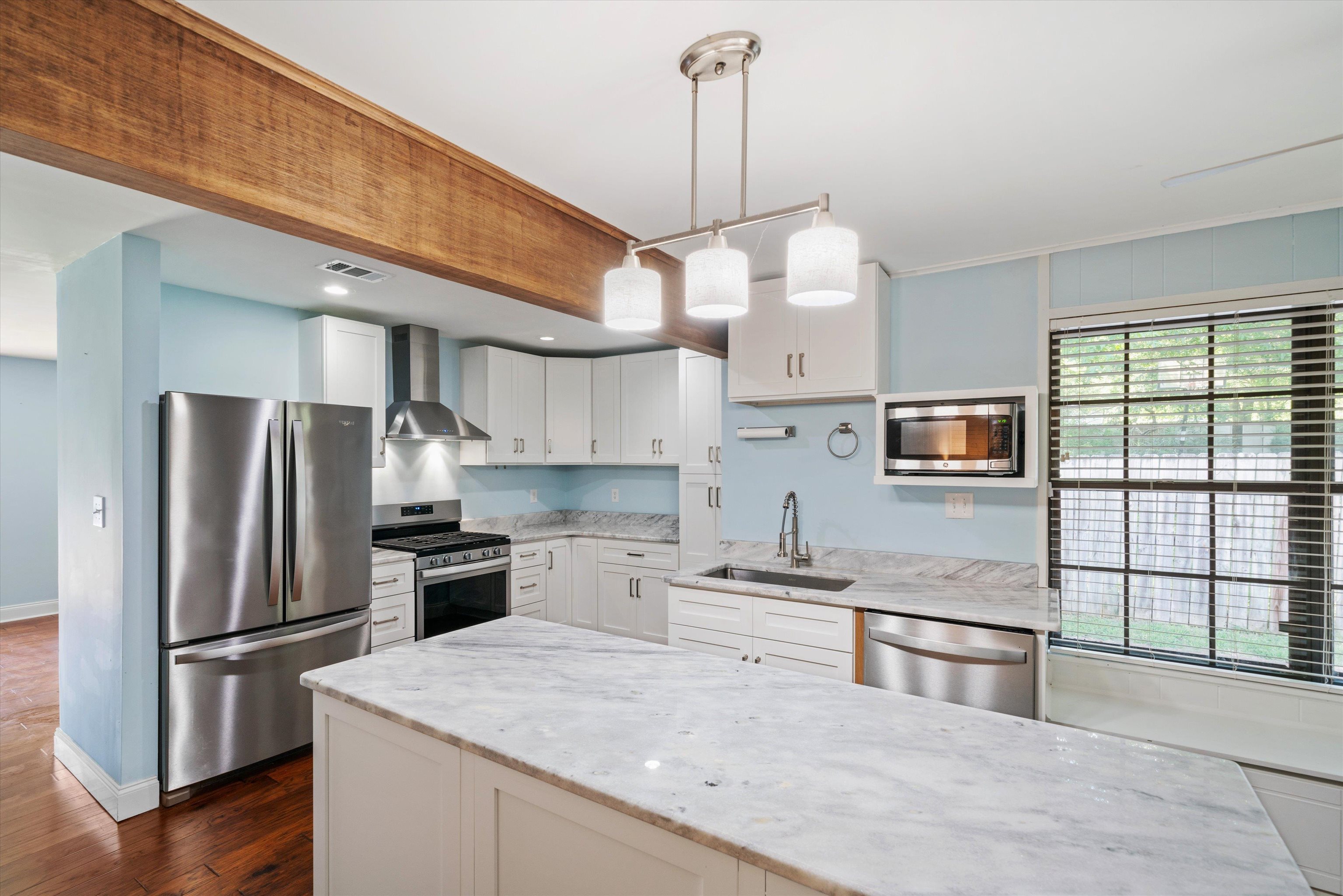 1348 Wilbec Road Memphis, TN 38117 - Photo 5 of 21 Kitchen with new cabinets, wall chimney range hood, light stone countertops, appliances with stainless steel finishes, decorative light fixtures and island.