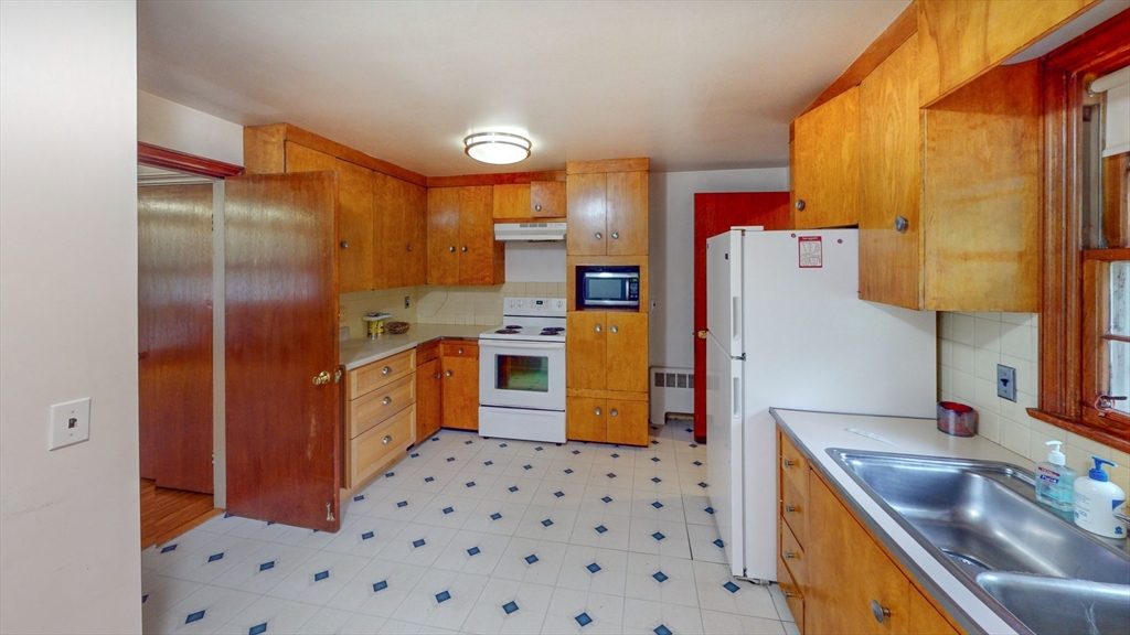 116 Lincoln Road Wayland, MA 01778 - Photo 5 of 26 a kitchen with stainless steel appliances a refrigerator a sink a stove and white cabinets