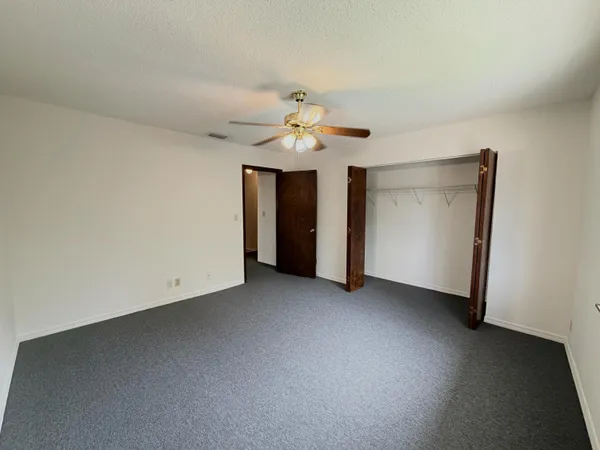 an empty room with a ceiling fan and a window
