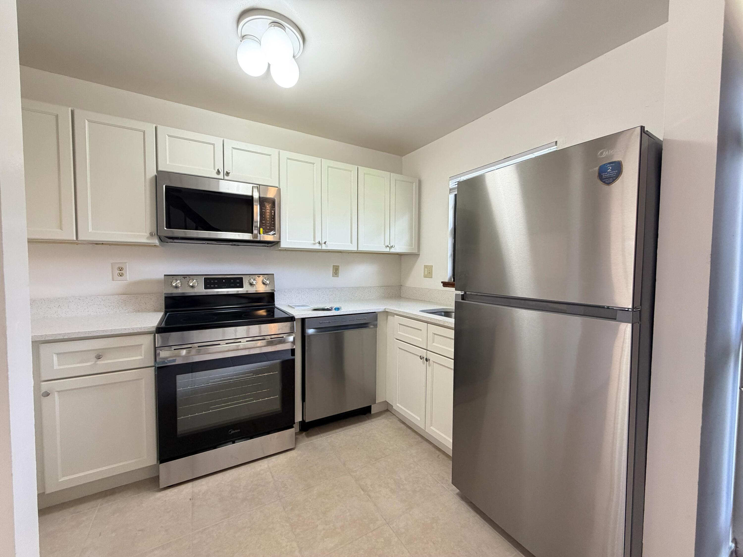 1226 Haverhill Road, Unit 3 Haverhill, FL 33417 - Photo 2 of 18 a kitchen with refrigerator a microwave a stove and cabinets