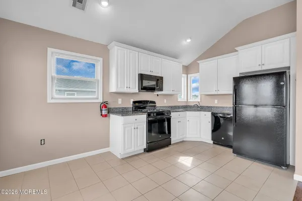 a kitchen with granite countertop a refrigerator and a stove top oven