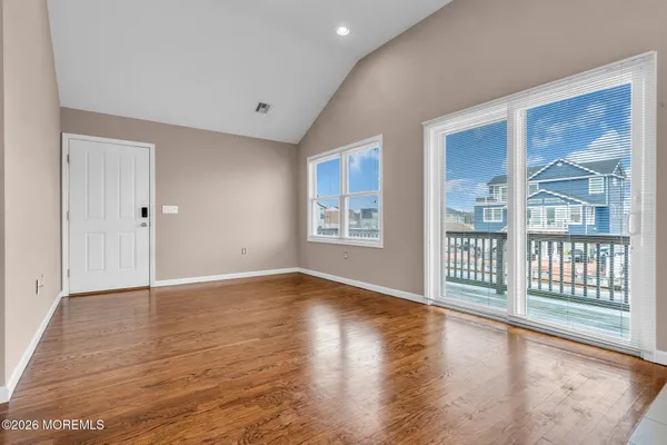 a view of an empty room with glass door and wooden floor
