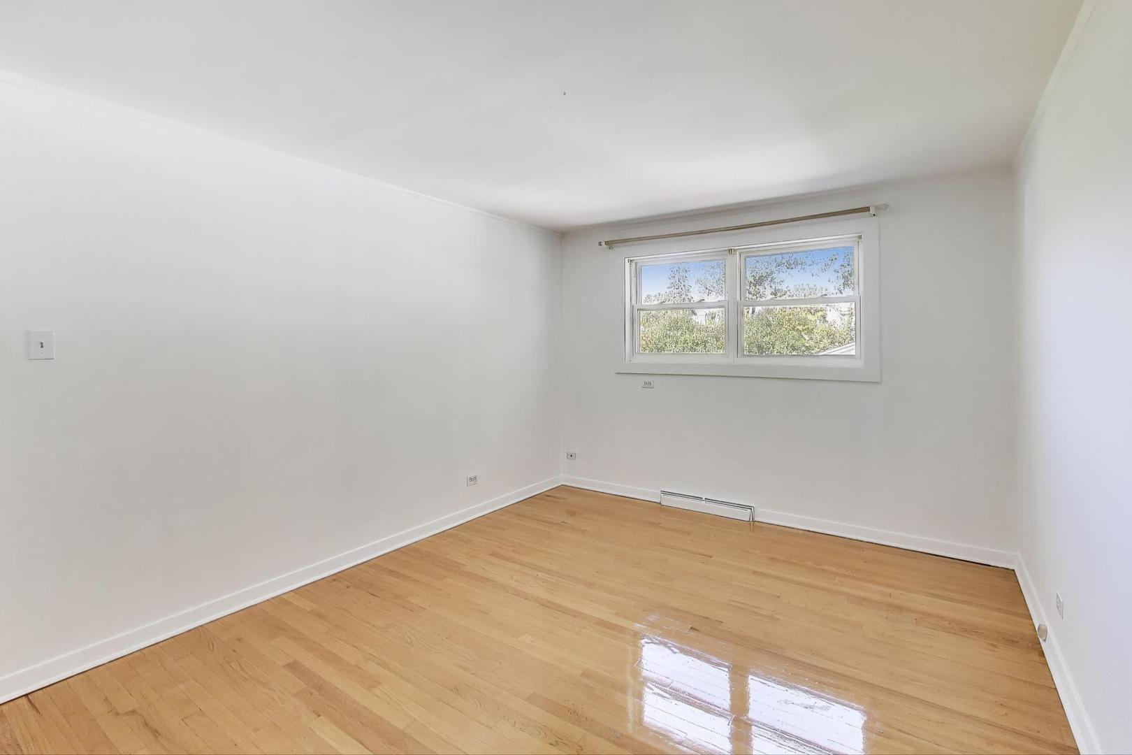 7332 Davis Street Morton Grove, IL 60053 - Photo 9 of 30 a view of an empty room with wooden floor and a window