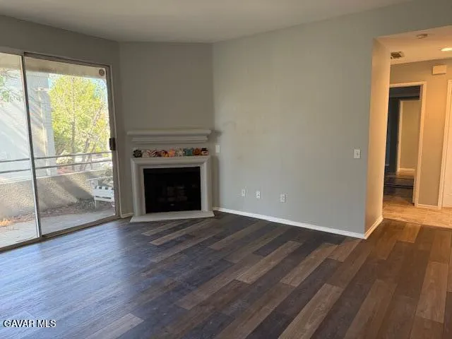 an empty room with wooden floor a fireplace and windows
