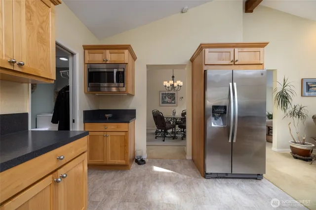 a living room with stainless steel appliances furniture a large window and a kitchen view