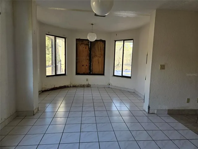 a view of an empty room with window and chandelier fan