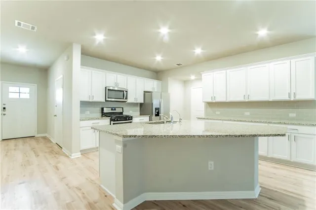 a kitchen with stainless steel appliances granite countertop a sink a stove a refrigerator and a microwave