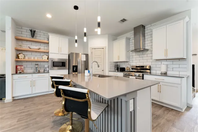 a kitchen with a sink a stove a refrigerator cabinets and a dining table