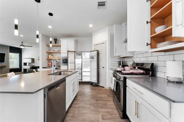 a kitchen with stainless steel appliances granite countertop a sink a stove and a refrigerator