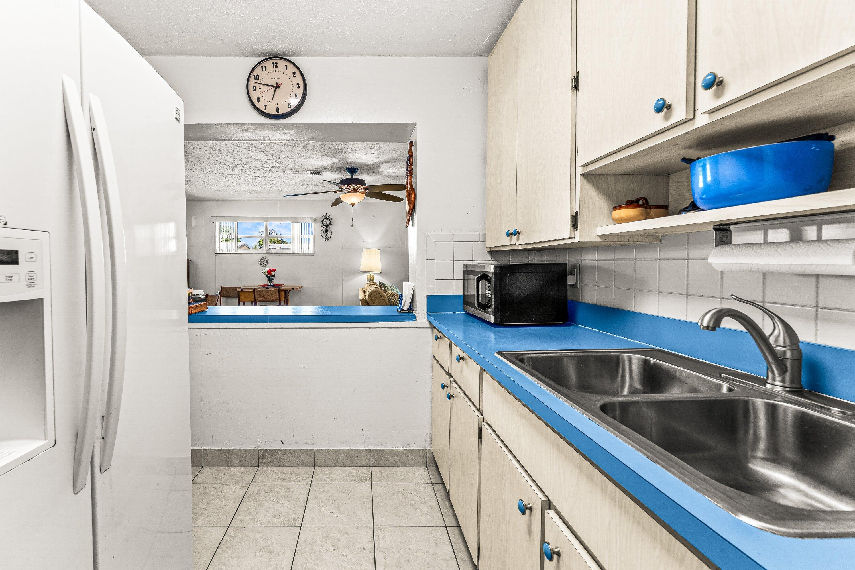 1040 West 1st Street Riviera Beach, FL 33404 - Photo 9 of 26 a kitchen with stainless steel appliances a sink a stove and a refrigerator with white cabinets