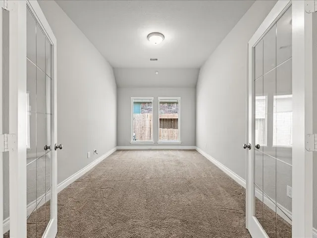 an empty room with windows and fan