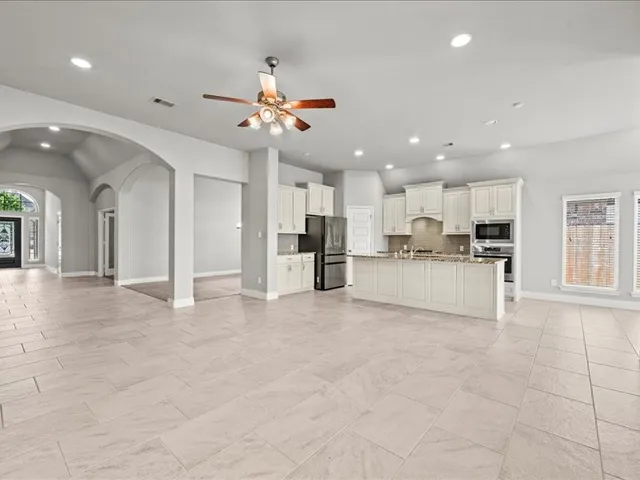 a view of large kitchen with a sink and refrigerator