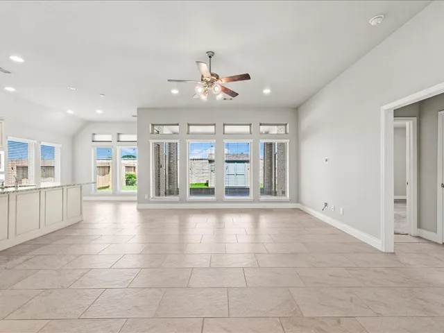 a view of an empty room with kitchen and window