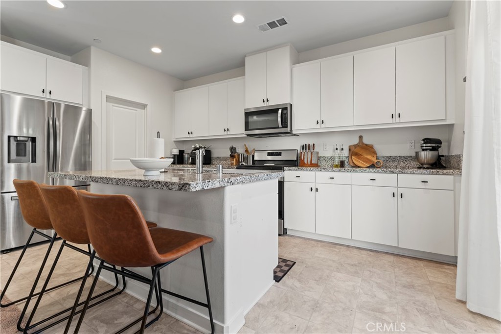 12704 Ironstone Way Moreno Valley, CA 92555 - Photo 24 of 38 a kitchen with stainless steel appliances granite countertop a white cabinets a sink and a refrigerator