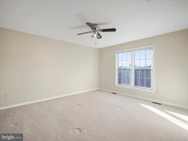 an empty room with a window and a ceiling fan