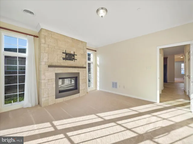 an empty room with chandelier fan and windows