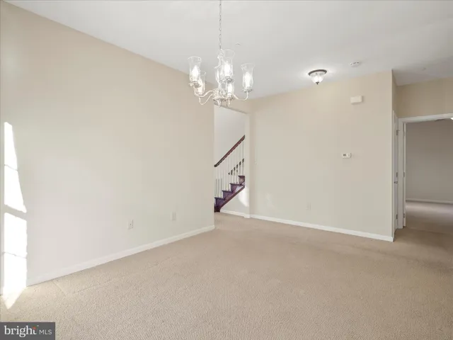 a room with kitchen island stainless steel appliances furniture a chandelier and a view of kitchen