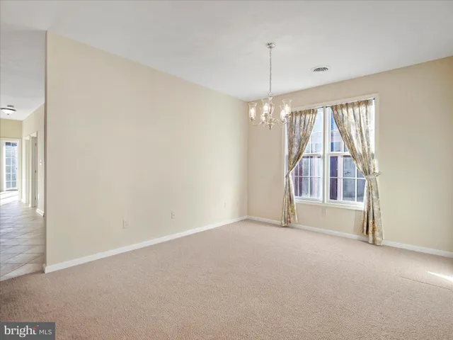 a view of empty room with window and chandelier