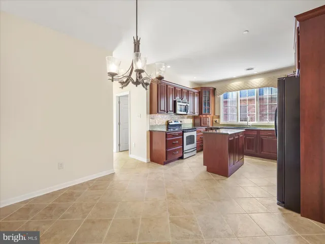 a room with a kitchen island stainless steel appliances a cabinet and a window