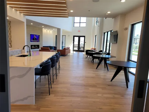 a dining hall with stainless steel appliances kitchen island granite countertop a table chairs and a refrigerator