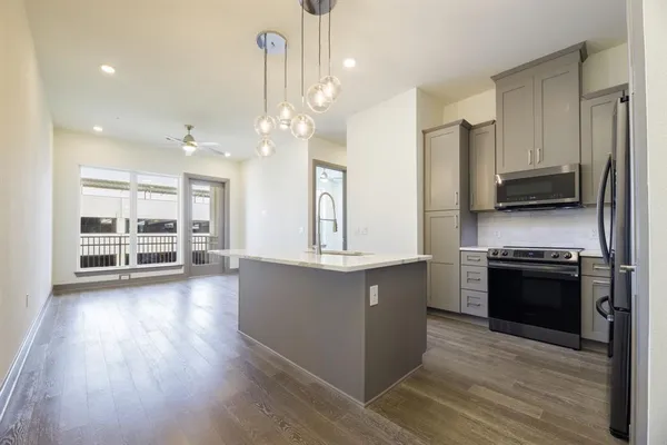 a large kitchen with stainless steel appliances granite countertop a stove and a wooden floors