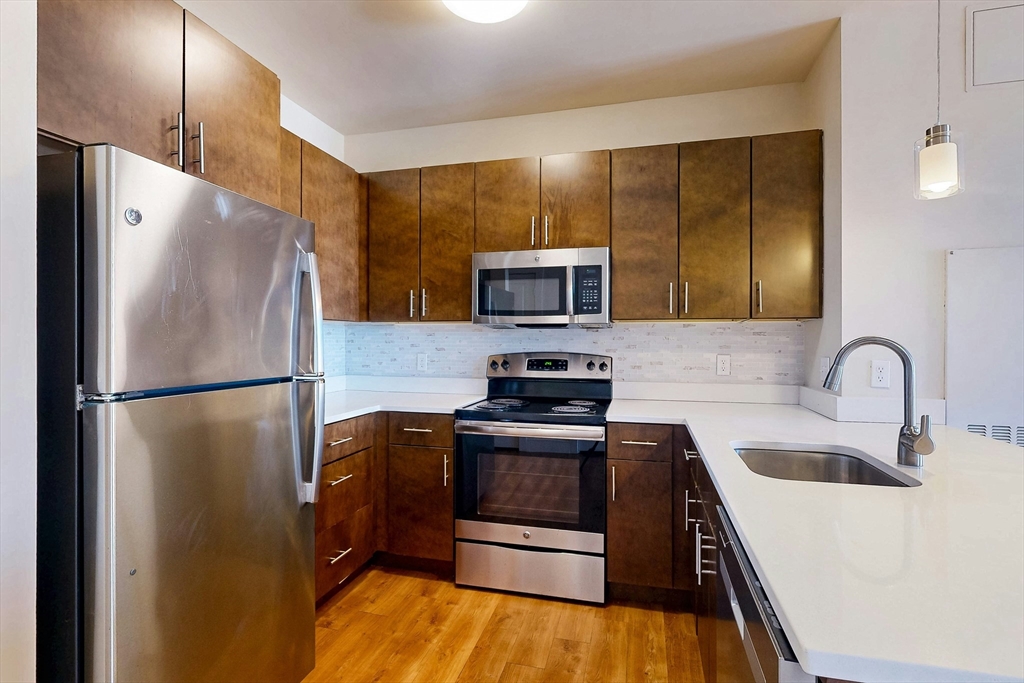 446 Cambridge Street, Unit 406 Boston, MA 02134 - Photo 2 of 7 a kitchen with stainless steel appliances a refrigerator a sink a stove and cabinets