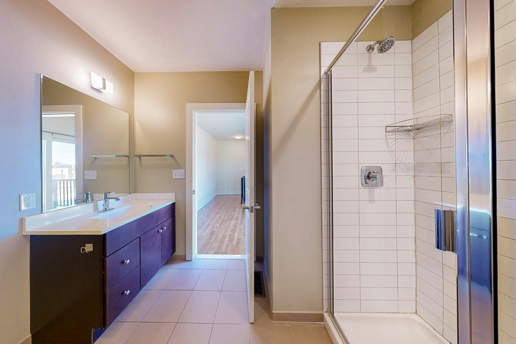 446 Cambridge Street, Unit 406 Boston, MA 02134 - Photo 6 of 7 a bathroom with a double vanity sink a large mirror and shower