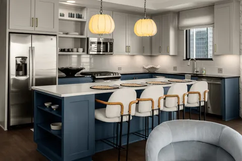 a kitchen with stainless steel appliances granite countertop a sink a stove a refrigerator cabinets and chairs