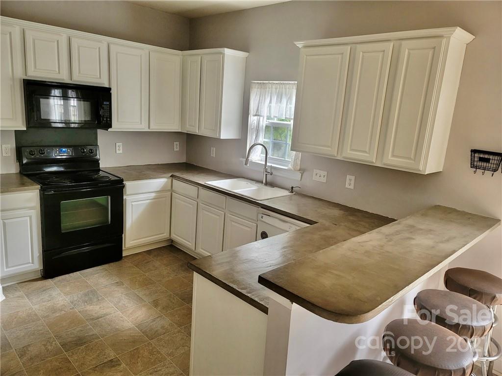 11402 Woodfire Road Charlotte, NC 28269 - Photo 13 of 24 a kitchen with stainless steel appliances granite countertop a sink a stove and a microwave